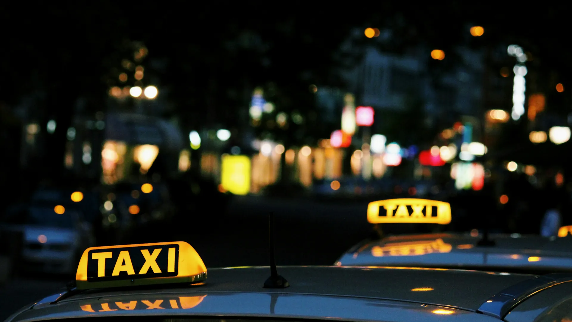 Leuchtende Taxischilder im abendlichen Stadtverkehr